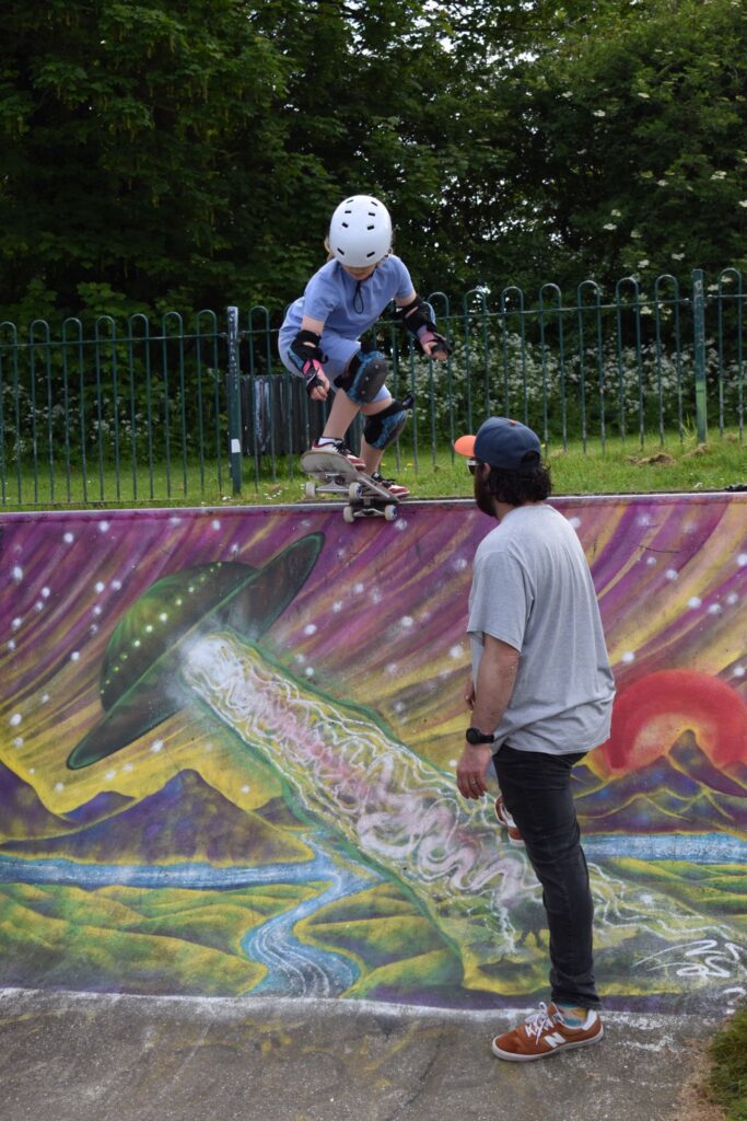 Skateboard coach Rick observing a student as they prepare to drop in on a ramp during a lesson.