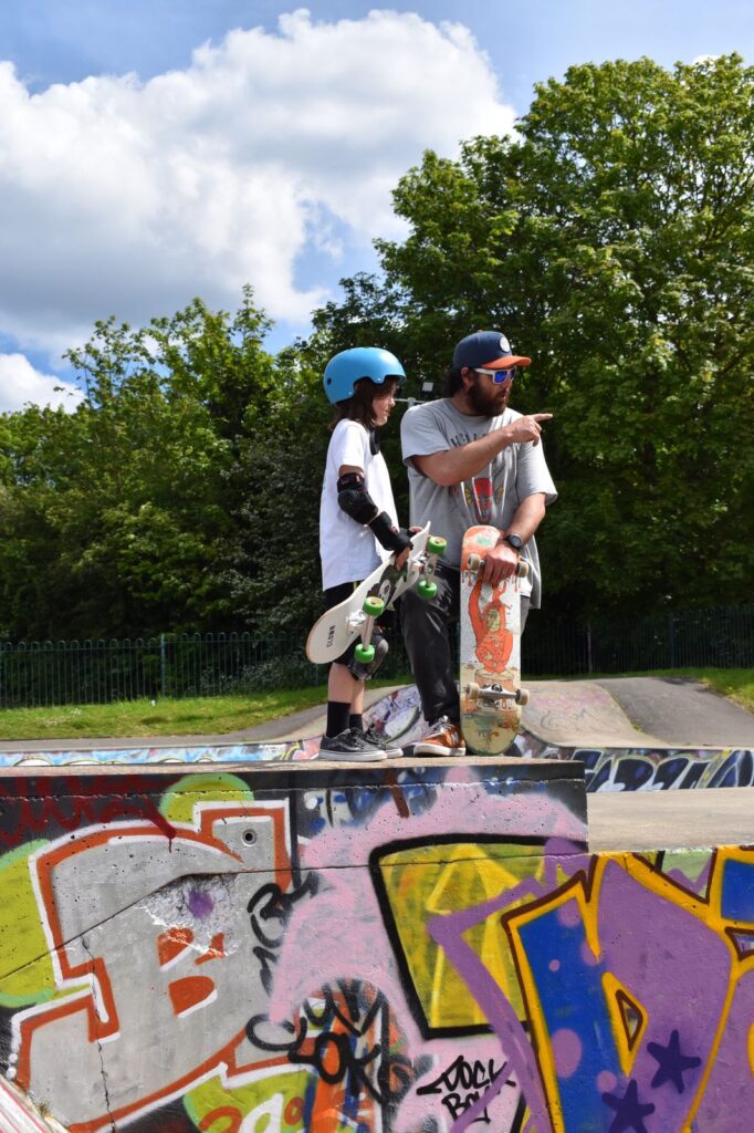Skateboard coach Rick talking with a student at the top of a ramp during a lesson.