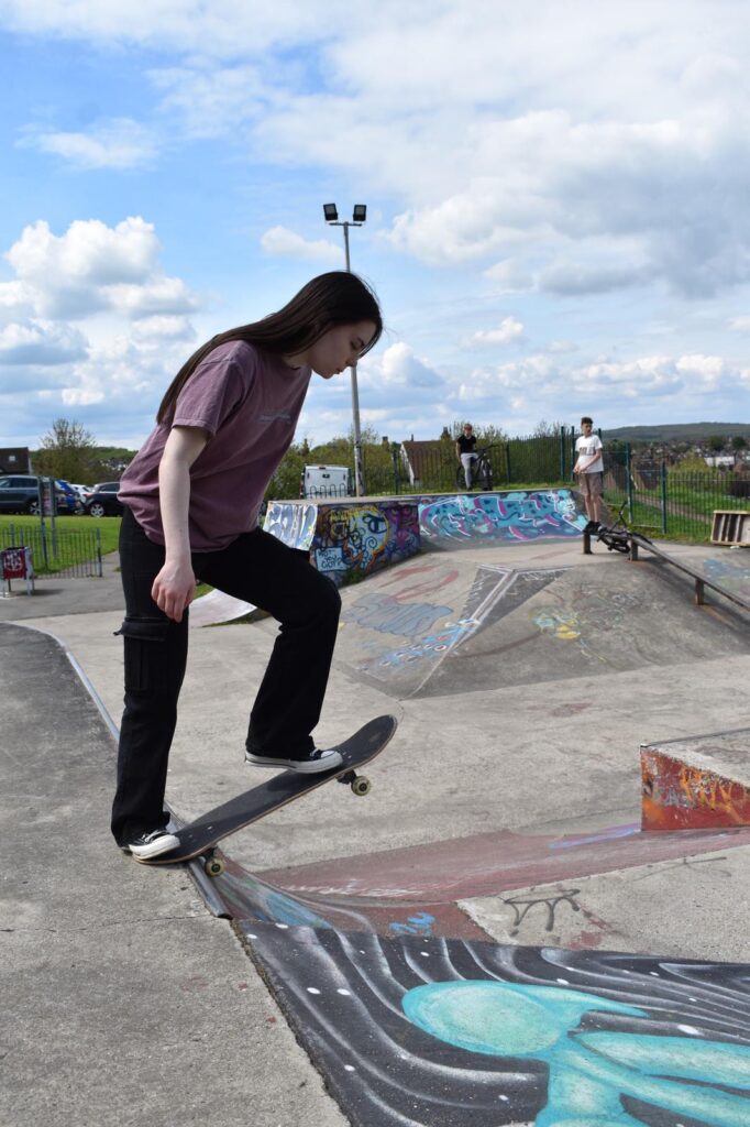 Skateboard student dropping in on a ramp by herself during a lesson.