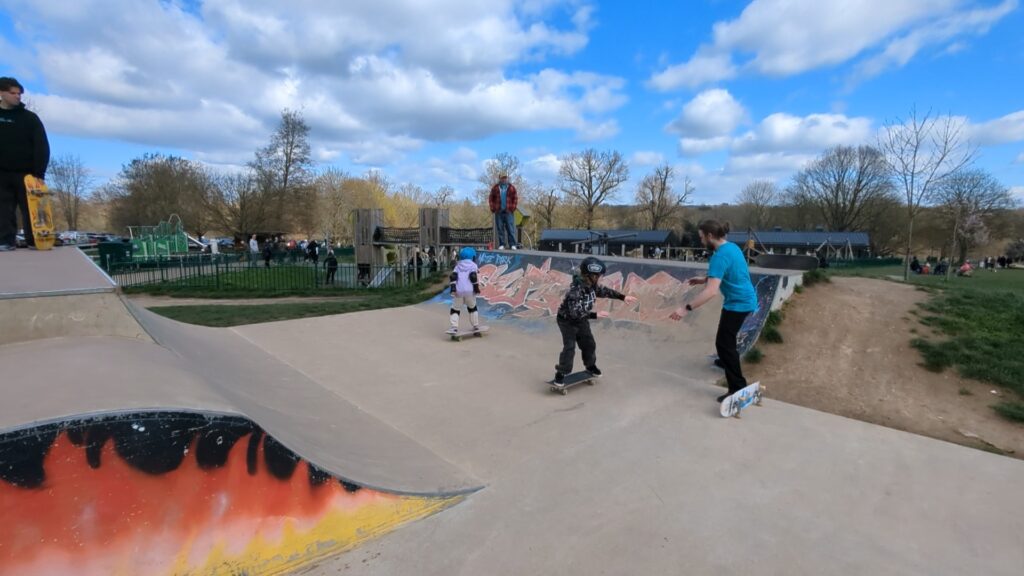 Coach Chris is helping a student Jase, drop in on the small quarter pipe at mote park skatepark