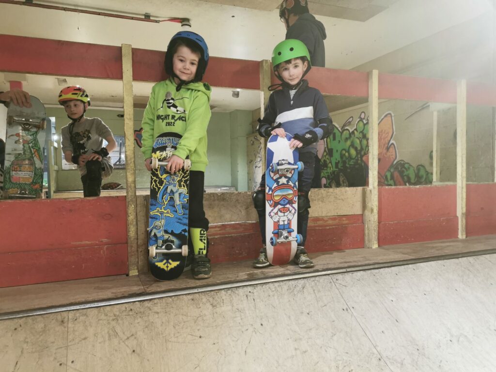 Two of our learners, standing on top of a small quarter pipe during one of our skateboarding lessons at unit 1 skatepark