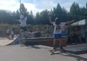 Two skateboard students jumping off a ledge during a skateboarding lesson.