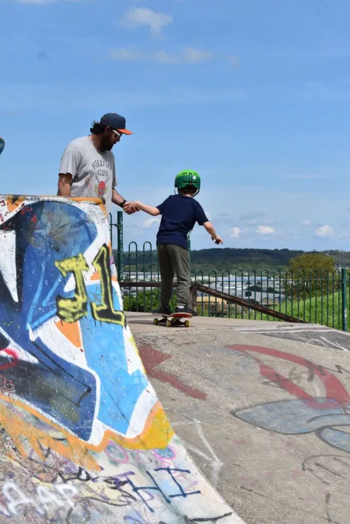 Skateboard coach assisting a child as they ride down a ramp during a skateboarding lesson