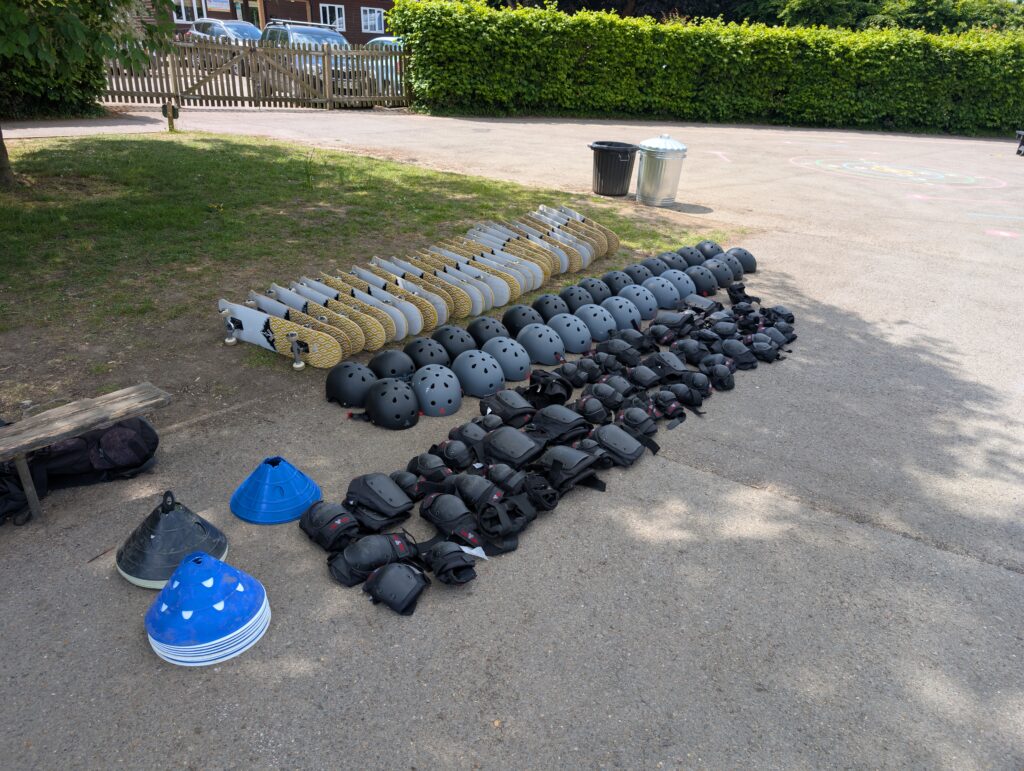Skateboarding equipment including helmets, knee pads, and skateboards neatly arranged on a floor ready for a lesson.