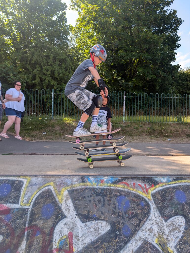 Skateboarding coach balancing and riding four skateboards stacked on top of each other during a skateboarding demonstration.