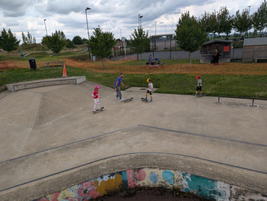Skateboard coach talking with three students at Cyclopark Skatepark during a skateboarding lesson.